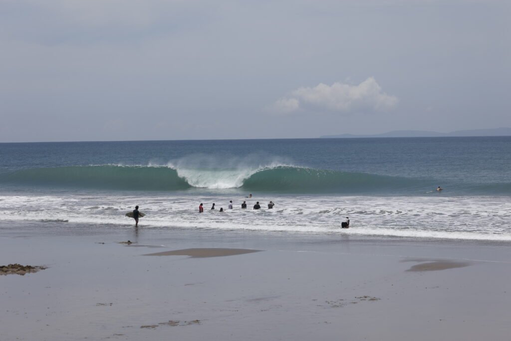 People on the beach with a perfect barrel on the back. Manta, Ecuador